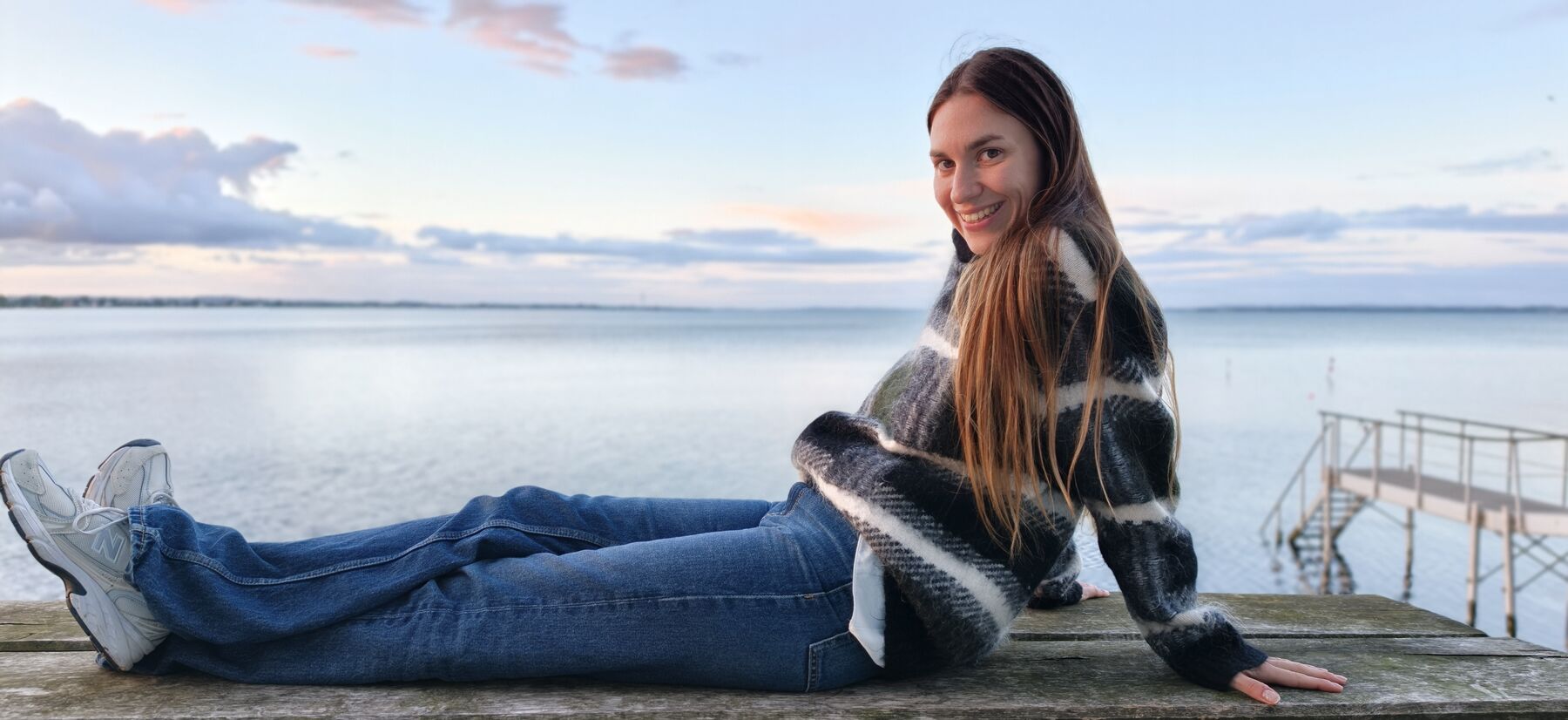 Olga sitting on a jetty by the sea